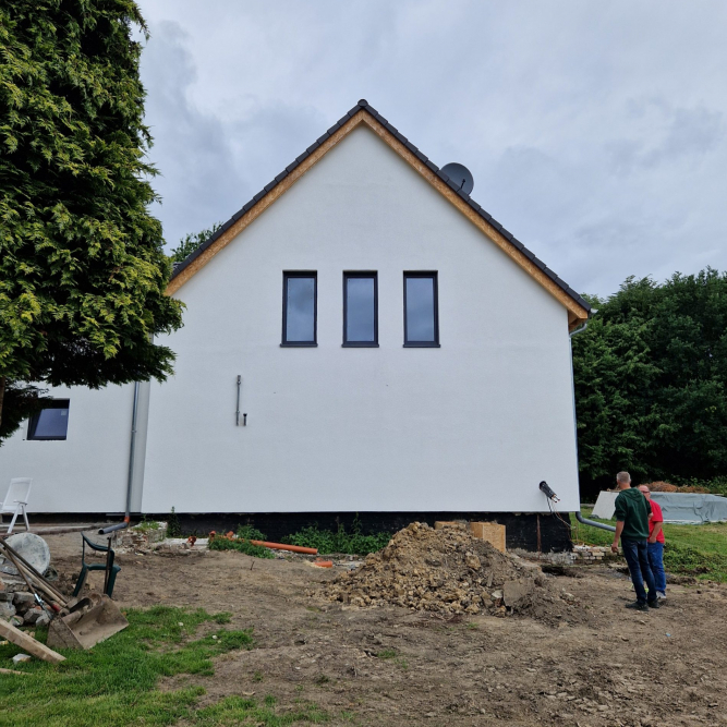 Giebelansicht der ehemaligen Scheune. Im Obergeschoss sieht man 3 symmetrisch sitzende schmale, hohe Fenster