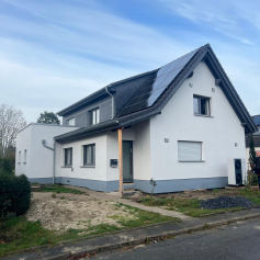 Außenansicht fertiges Haus, frisch gestrichen und mit PV Anlage